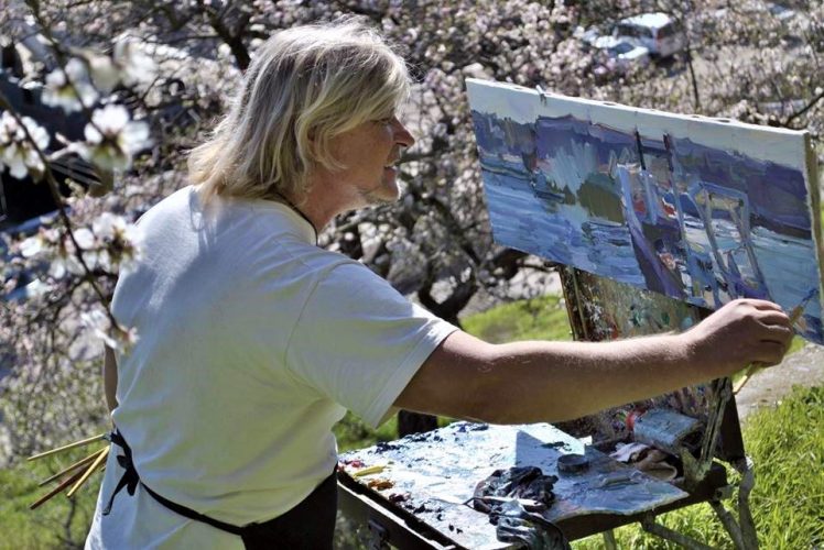 man outdoors painting flowers