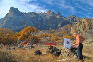 shirtless man painting mountains outdoors