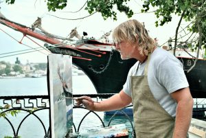 man painting ships outside