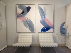 two paintings hanging over chairs