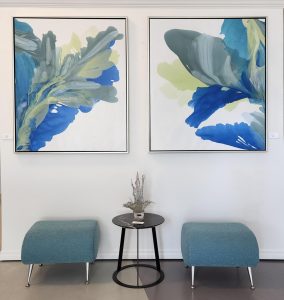 two blue green paintings hanging over two stools