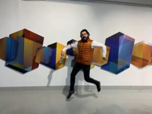 man jumping in front of geometric sculpture